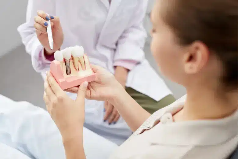 Dentist explaining a dental implant model to a patient